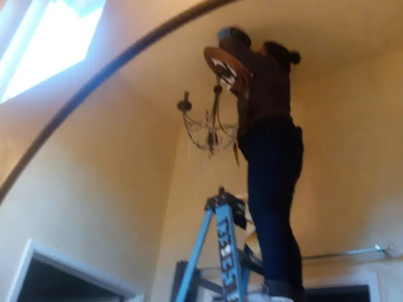 Electrician installing a chandelier in a Worth residence